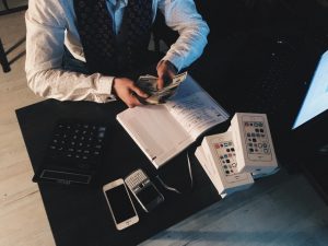 Section Debt Refinancing person counting money with smartphones in front on desk 210990 300x225